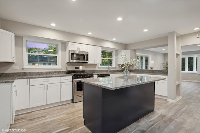 kitchen featuring white cabinets, a kitchen island, stainless steel appliances, and light wood-type flooring