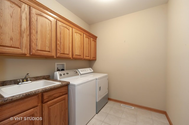 laundry area with washer and clothes dryer, light tile patterned flooring, cabinets, and sink