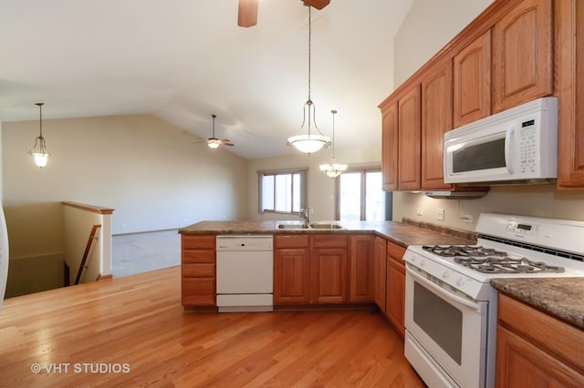 kitchen with sink, hanging light fixtures, light hardwood / wood-style floors, vaulted ceiling, and white appliances