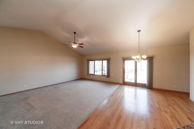 unfurnished room with ceiling fan with notable chandelier, light hardwood / wood-style flooring, and vaulted ceiling