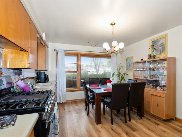 dining area with light hardwood / wood-style floors, sink, and an inviting chandelier