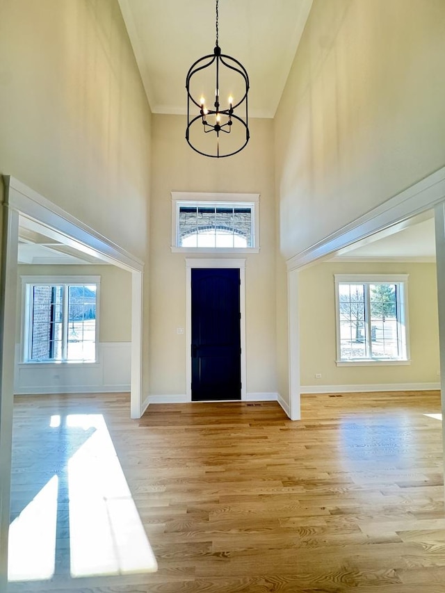 entryway featuring plenty of natural light, light wood-style flooring, a high ceiling, and an inviting chandelier