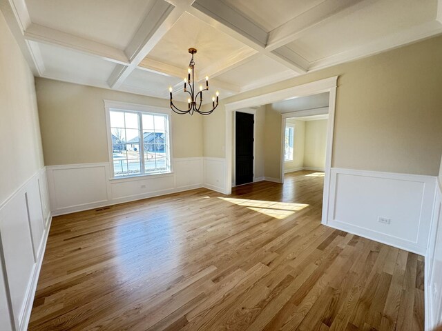 unfurnished living room with a wealth of natural light, a fireplace, a notable chandelier, and light wood-type flooring