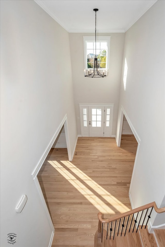 foyer featuring light hardwood / wood-style floors, crown molding, and a chandelier