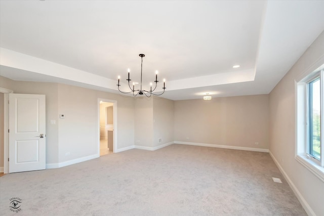 unfurnished room with a raised ceiling, a healthy amount of sunlight, and light colored carpet