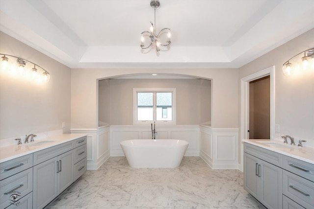 bathroom with vanity, a tub to relax in, and a raised ceiling