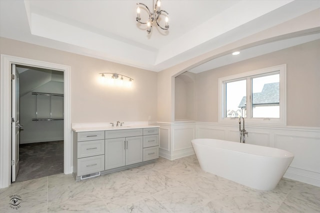 bathroom featuring a tray ceiling, a bathtub, and vanity