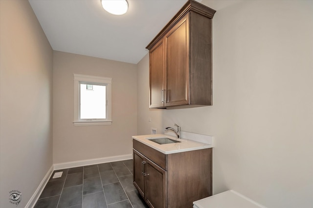 laundry area featuring hookup for a washing machine, dark tile patterned floors, cabinets, and sink