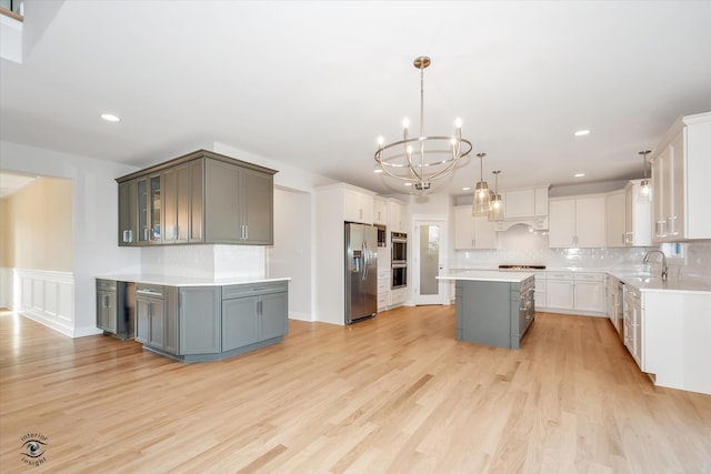 kitchen featuring gray cabinetry, a center island, light hardwood / wood-style flooring, appliances with stainless steel finishes, and decorative light fixtures