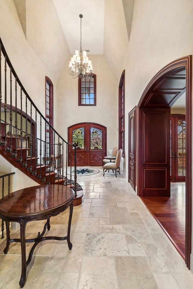 entrance foyer featuring hardwood / wood-style flooring, an inviting chandelier, high vaulted ceiling, and french doors