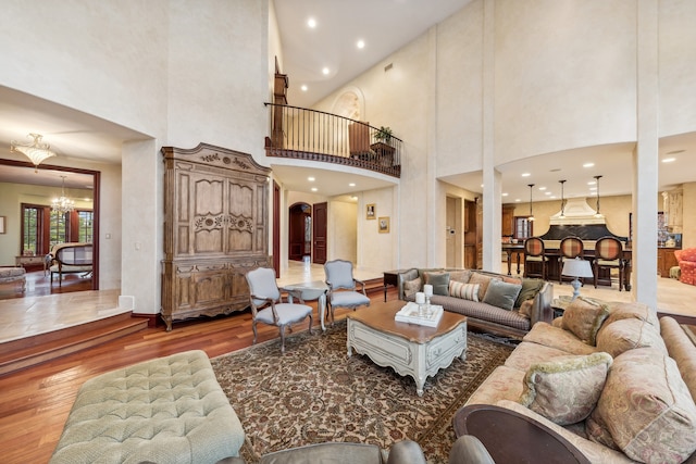 living room with hardwood / wood-style floors, a notable chandelier, and a high ceiling