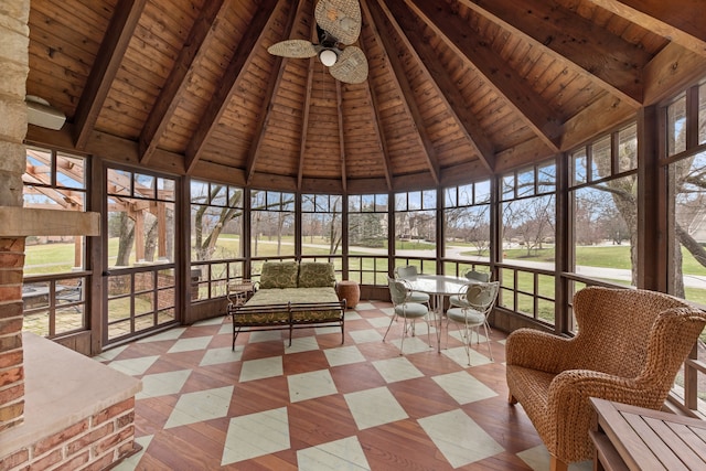 unfurnished sunroom featuring vaulted ceiling with beams, a wealth of natural light, ceiling fan, and wooden ceiling