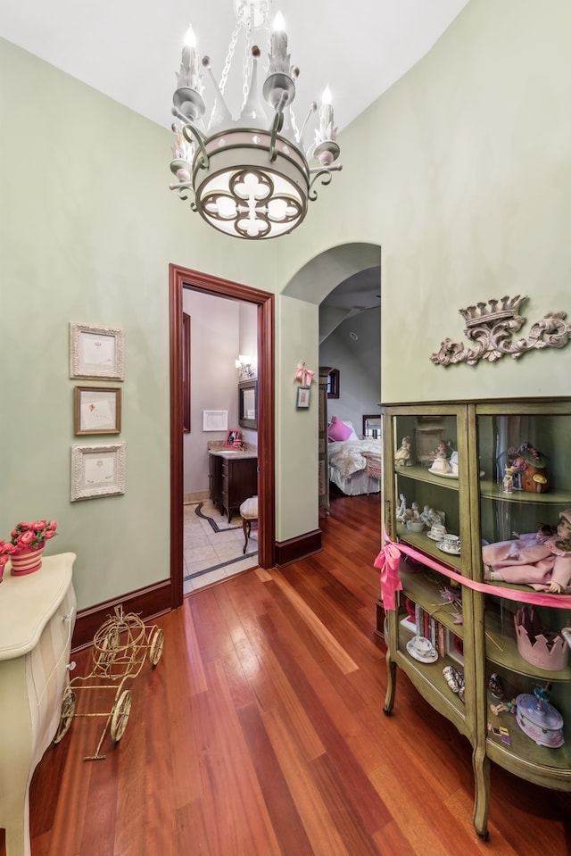 corridor featuring a chandelier, hardwood / wood-style floors, and lofted ceiling