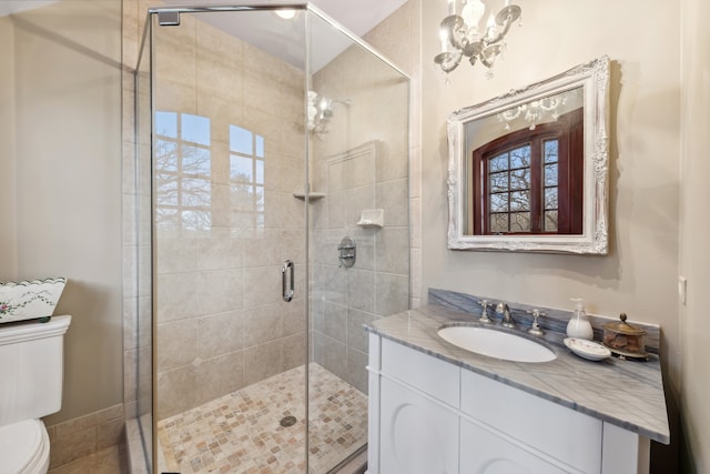 bathroom with vanity, toilet, an enclosed shower, and an inviting chandelier