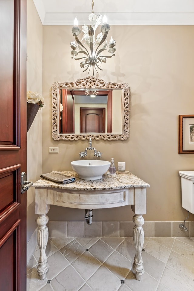 bathroom featuring an inviting chandelier, crown molding, and sink