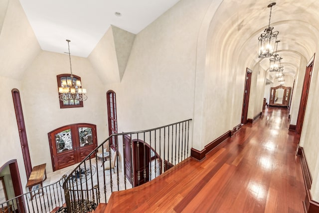 hall featuring french doors, wood-type flooring, lofted ceiling, and a notable chandelier