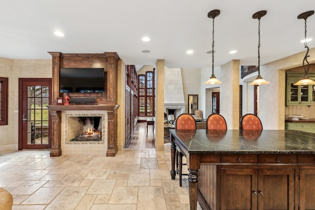 kitchen featuring a breakfast bar area, a tiled fireplace, and hanging light fixtures