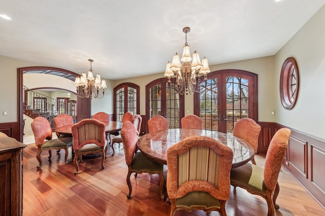 dining space with french doors, a notable chandelier, and light wood-type flooring