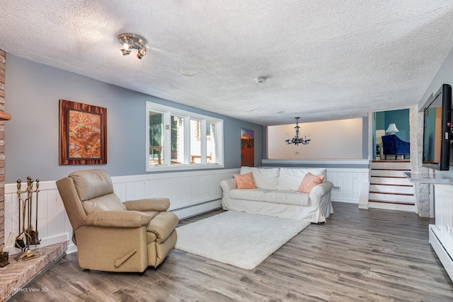 8542 W 132nd Pl, Palos Park, IL 60464 - living room featuring a baseboard heating unit, wood finished floors, wainscoting, a textured ceiling, and a chandelier