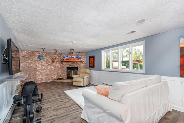 8542 W 132nd Pl, Palos Park, IL 60464 - living area featuring a textured ceiling, a brick fireplace, a wainscoted wall, brick wall, and wood finished floors