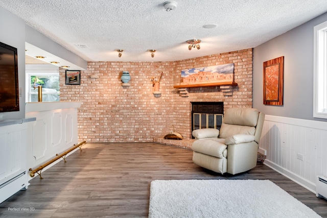 8542 W 132nd Pl, Palos Park, IL 60464 - living area with brick wall, baseboard heating, a textured ceiling, wood finished floors, and a brick fireplace
