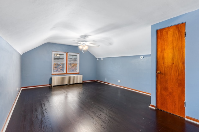 additional living space with vaulted ceiling, radiator, ceiling fan, and dark hardwood / wood-style floors