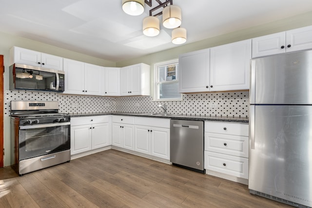 kitchen featuring white cabinetry, sink, dark wood-type flooring, stainless steel appliances, and tasteful backsplash