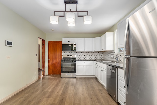 kitchen featuring white cabinetry, sink, stainless steel appliances, light hardwood / wood-style flooring, and decorative light fixtures