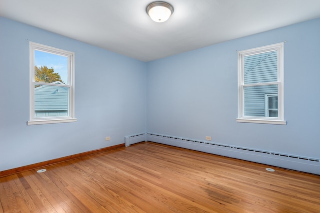 unfurnished room with light hardwood / wood-style flooring and a baseboard heating unit