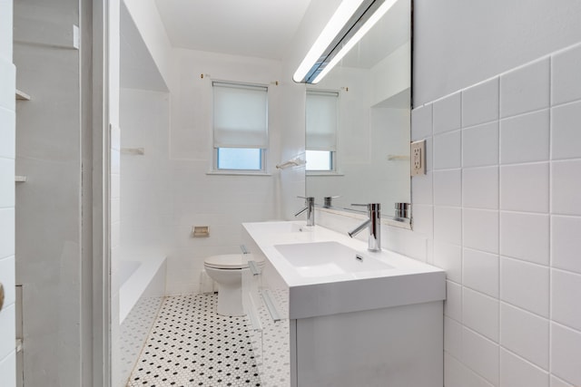 bathroom with a washtub, vanity, toilet, and tile walls