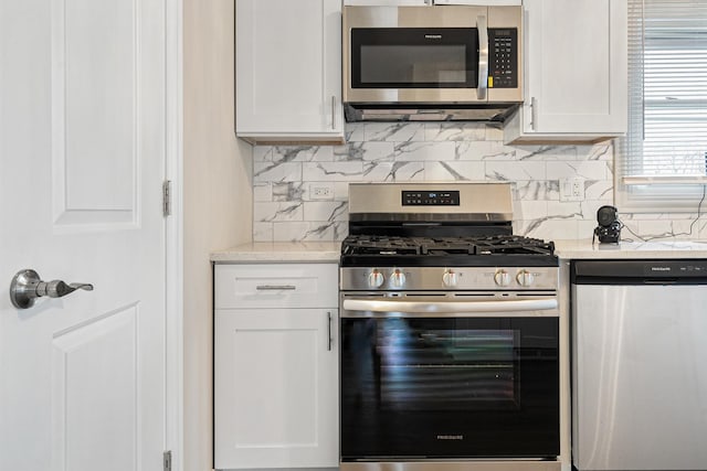 kitchen featuring white cabinetry, appliances with stainless steel finishes, light stone countertops, and backsplash