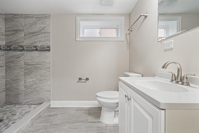 bathroom with vanity, toilet, and a tile shower