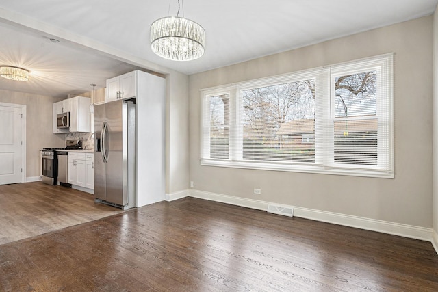 unfurnished dining area with a notable chandelier and dark hardwood / wood-style floors