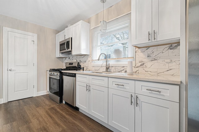 kitchen featuring dark wood-type flooring, sink, hanging light fixtures, stainless steel appliances, and white cabinets