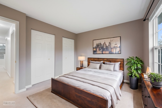 bedroom featuring two closets and light colored carpet