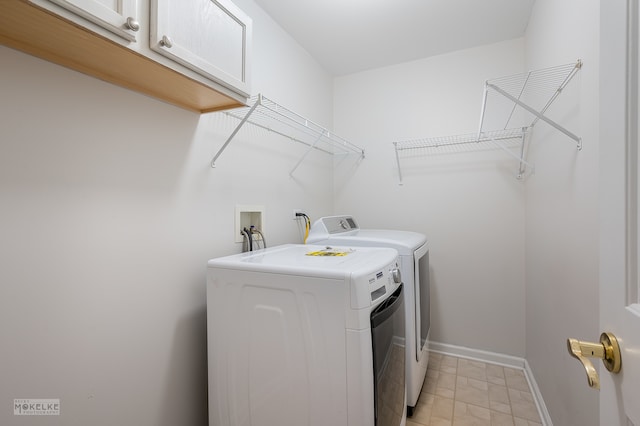 clothes washing area featuring cabinets and washer and clothes dryer