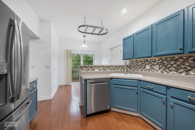 kitchen with stainless steel appliances, blue cabinets, sink, hardwood / wood-style flooring, and hanging light fixtures