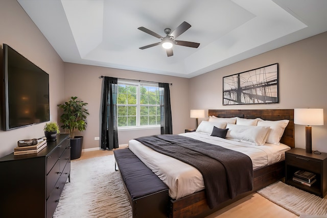 bedroom with a tray ceiling, ceiling fan, and light hardwood / wood-style floors