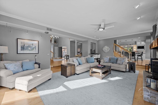 living room with ceiling fan, light wood-type flooring, and ornamental molding