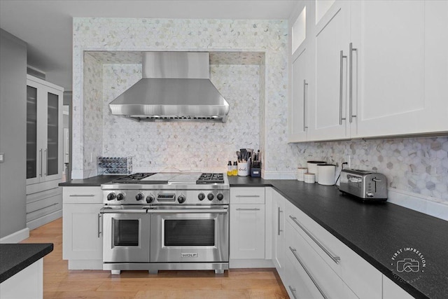 kitchen with backsplash, white cabinetry, double oven range, and wall chimney range hood