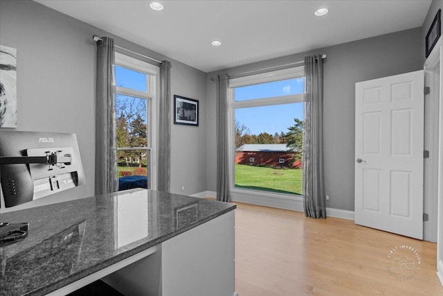 kitchen with dark stone counters and light hardwood / wood-style flooring