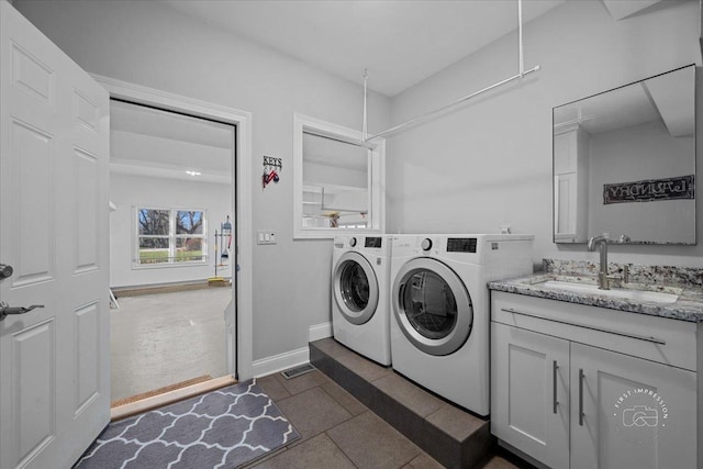 laundry area featuring washing machine and clothes dryer, dark tile patterned floors, and sink