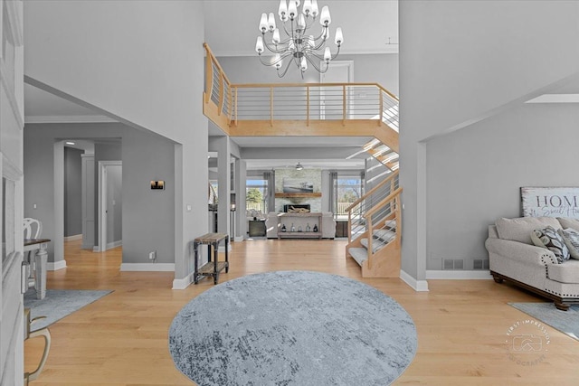 foyer with a chandelier, wood-type flooring, a towering ceiling, and ornamental molding