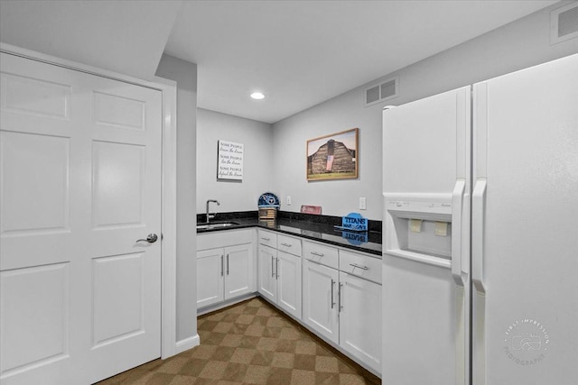 kitchen with white cabinets, white refrigerator with ice dispenser, and sink