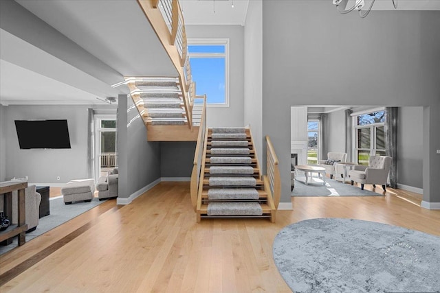 staircase featuring wood-type flooring, a notable chandelier, and ornamental molding