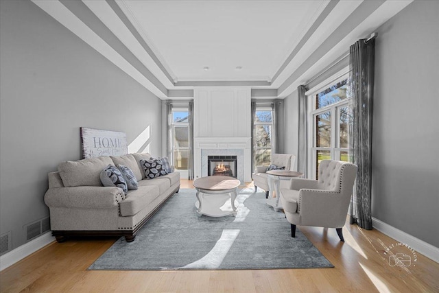 living room with ornamental molding, a tray ceiling, and light hardwood / wood-style flooring