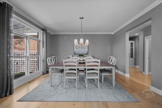 dining room with crown molding, a notable chandelier, and light wood-type flooring