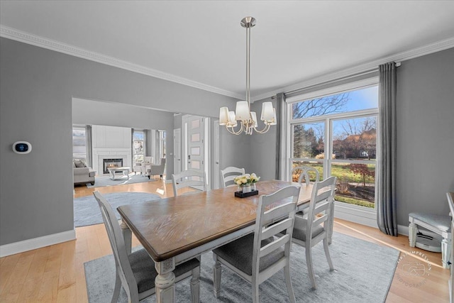 dining space featuring light wood-type flooring, ornamental molding, and a chandelier