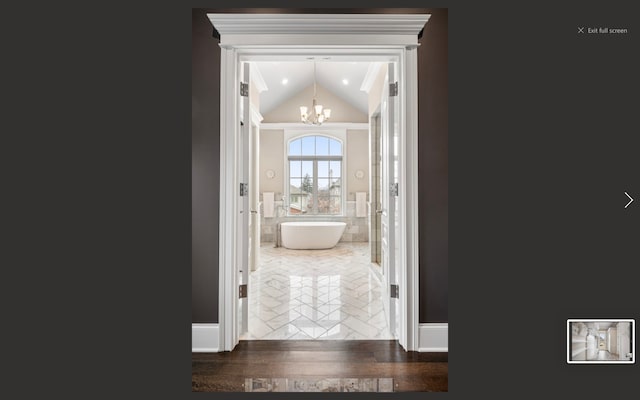 corridor featuring dark hardwood / wood-style flooring, an inviting chandelier, and lofted ceiling