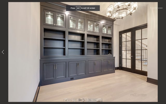 interior space featuring an inviting chandelier, light wood-type flooring, built in features, and french doors